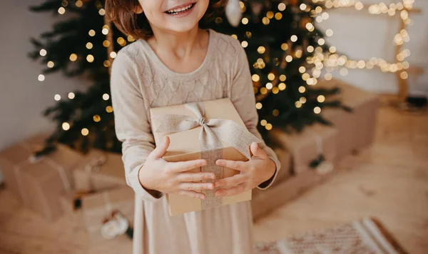Szczęśliwa Młoda Dziewczyna Nosi Przytulną Beżową Sukienkę Trzymając Prezent Świąteczny — Zdjęcie stockowe
