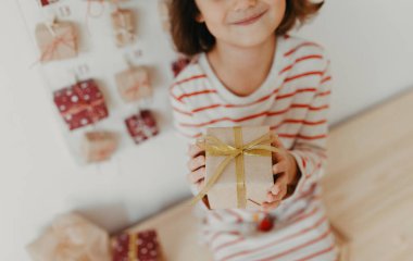 Noel hediyelerini elinde tutan tatlı bir kız. Çocuklar için paketlenmiş hediyeler. Mevsimlik gelenek. Çevre dostu Noel