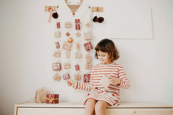 Noel hediyelerini açan tatlı kız. Çocuklar için paketlenmiş hediyeler. Mevsimlik gelenek. Çevre dostu Noel