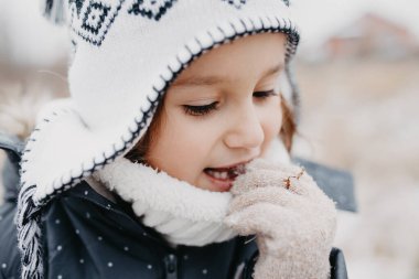 Karlı kış yürüyüşüne çıkan mutlu kız çocuğu. Havalı, siyah kar tulumu giyiyordu. Kış kıyafeti