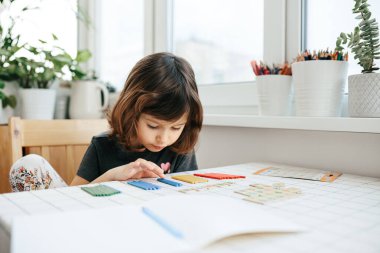 Kafkas bir kız sayısallığı öğreniyor, ekliyor - renkli mutfak çubuklarıyla sayıyor ve çıkarıyor. Erken matematik, bilişsel beceriler, öğrenme araçları, çocuk gelişimi, eğitim kavramı.