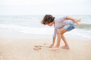 Beş yıl boyunca kumsalda kumlara resim çizen tatlı kıvırcık beyaz kız..