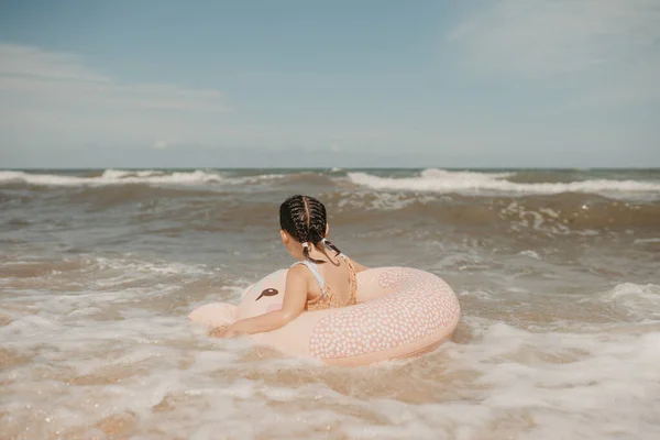 Дівчина в купальнику плаває з надувним плавальним кільцем, розважаючись у воді — стокове фото