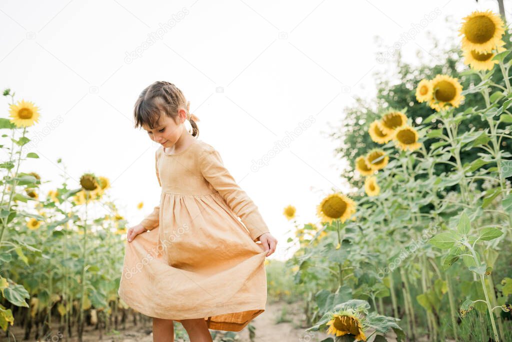 Happy child girl in the field of sunflowers