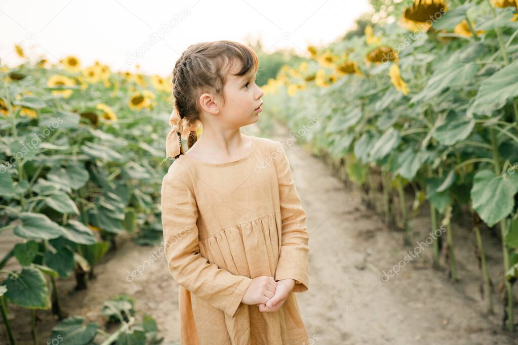 Happy child girl in the field of sunflowers