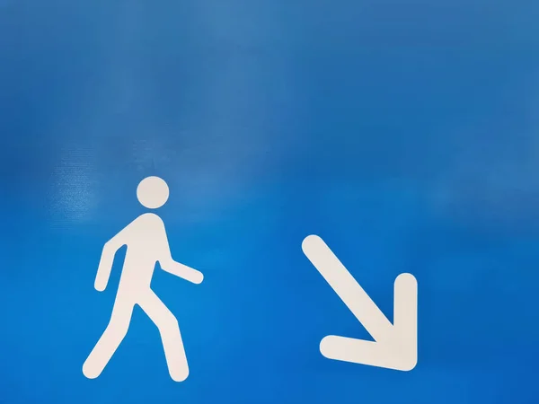 White Directional Symbol with Walking Man and Arrow Pointing to Down to the Right