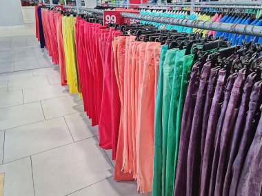 Renkli Pantolonlar Giyim mağazasında askıda asılı duruyor.