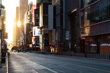 NEW YORK CITY, ABD - 14 Haziran 2020: Arkaplanda Times Meydanı 'nın renkli tabelaları ve reklam panolarının yer aldığı 42. Cadde' nin boş bir manzarasında gün batımı ışığı parlıyor.