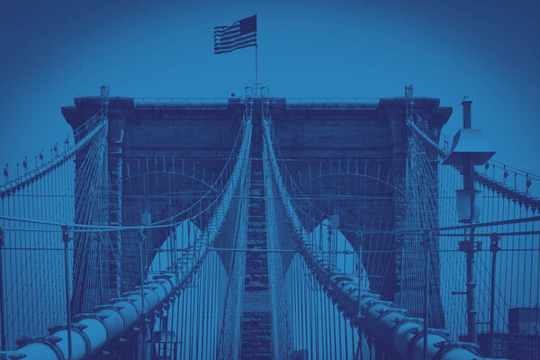 Brooklyn Bridge with American flag in Manhattan, New York City with colorful blue monotone color effect