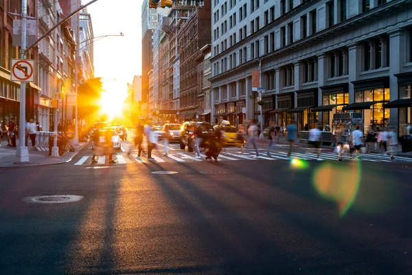 マンハッタンの5番街の忙しい交差点を渡る人々の群衆の上に輝く夕日の明るい光ニューヨーク市 — ストック写真