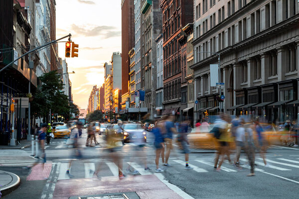 Busy people walk across the crowded intersection on 23rd Street and Fifth Avenue in Manhattan, New York City NYC