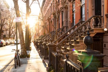 New York 'un West Village semtindeki Charles Caddesi' ndeki tarihi binalar. Boş kaldırımda öğleden sonra güneş ışığı parlıyor.
