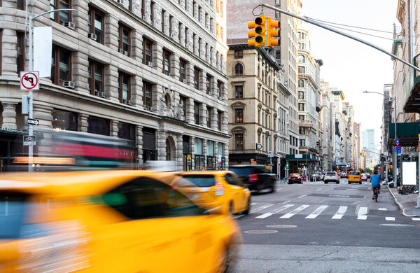 Busy street scene in Manhattan with Taxi speeding down 5th Avenue through New York City NYC