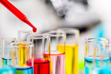 Test tüpü damlatıcısında kırmızı su damlası. Renkli sıvının üzerinde. Kopya alanı olan tüp camda..