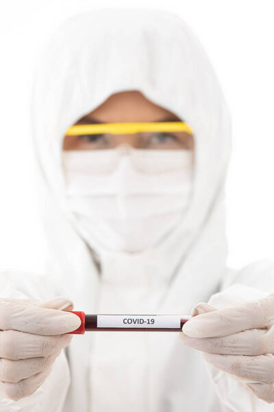 Scientist in sterilizes lab coat cloth holding Covid-19 test tube sample in hand. Selective focus on the name of virus. Concept for medical people trying and researching for win over coronavirus.