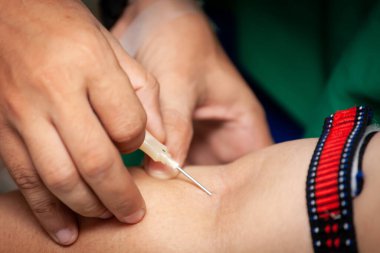 Hemşirenin eli, kan bağışçısı koluna iğne batırıyor..