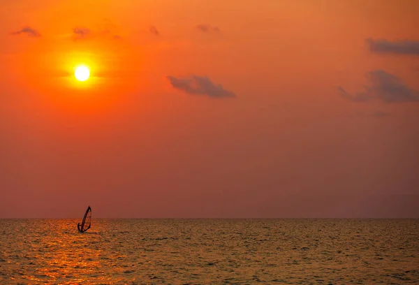 サーファープレイフロントで波と夕暮れの海で一人でウィンドサーフィン — ストック写真