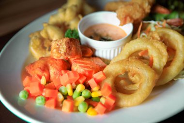 Sebzeli balık bifteği ve beyaz tabakta aperatif.