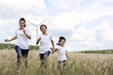 Anne ve oğlu arka planda büyük bir rüzgar türbiniyle oynuyorlar.