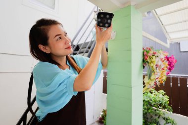 Güzel bir kadın evi, güvenlik kamerasının ve internet kamerasının görüş açısını mükemmel bir izleme sahnesi için ayarlar. Modern ev kadınının kendine güvenen ve kendine güvenen işi..