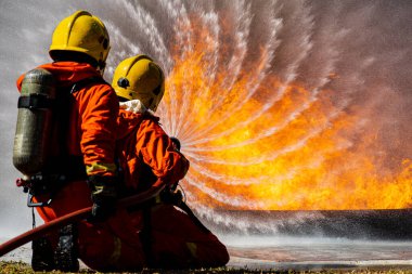 İki itfaiyeciden oluşan bir itfaiye ekibi oksijen tankı sırtında su dökerek açık hava felaketlerinin yaşandığı bölgede cesur ve sorumluluk sahibi büyük turuncu bir ateşe göğüs gerdiler.