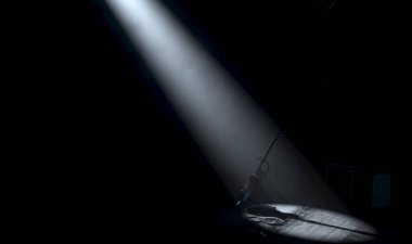 Bir müzik konseri sahnesinde dinlenen bir elektro gitar. Karanlık bir arkaplanda tek bir dramatik sahne ışığıyla aydınlatılıyor.