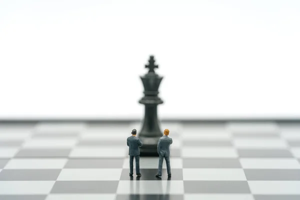 Miniaturní Obchodníci Stojící Šachovnici Šachovou Figurkou Zádech Jako Obchodní Koncept — Stock fotografie
