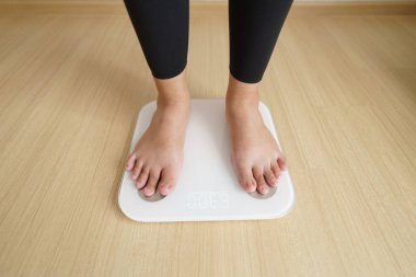 Elektronik terazinin üzerinde duran kadın kontrol ağırlığı için tartılıyor. diyet yaşam tarzı konsepti, karın ve kilo kontrol kavramını azaltmak için.