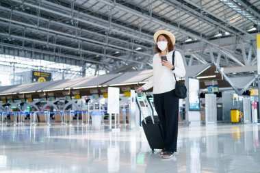 Yüz maskesi takan yeni normal turist havaalanında seyahat ediyor. Covid-19 'dan sonra yeni bir yaşam tarzı yolculuğu. Sosyal uzaklık sağlık sistemi, dikkatli olun ve seyahat balonu konsepti.