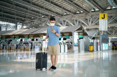 Yüz maskesi takan yeni normal turist havaalanında seyahat ediyor. Covid-19 'dan sonra yeni bir yaşam tarzı yolculuğu. Sosyal uzaklık sağlık sistemi, dikkatli olun ve seyahat balonu konsepti.