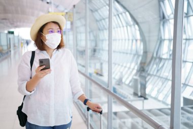 Yüz maskesi takan yeni normal turist havaalanında seyahat ediyor. Covid-19 'dan sonra yeni bir yaşam tarzı yolculuğu. Sosyal uzaklık sağlık sistemi, dikkatli olun ve seyahat balonu konsepti.