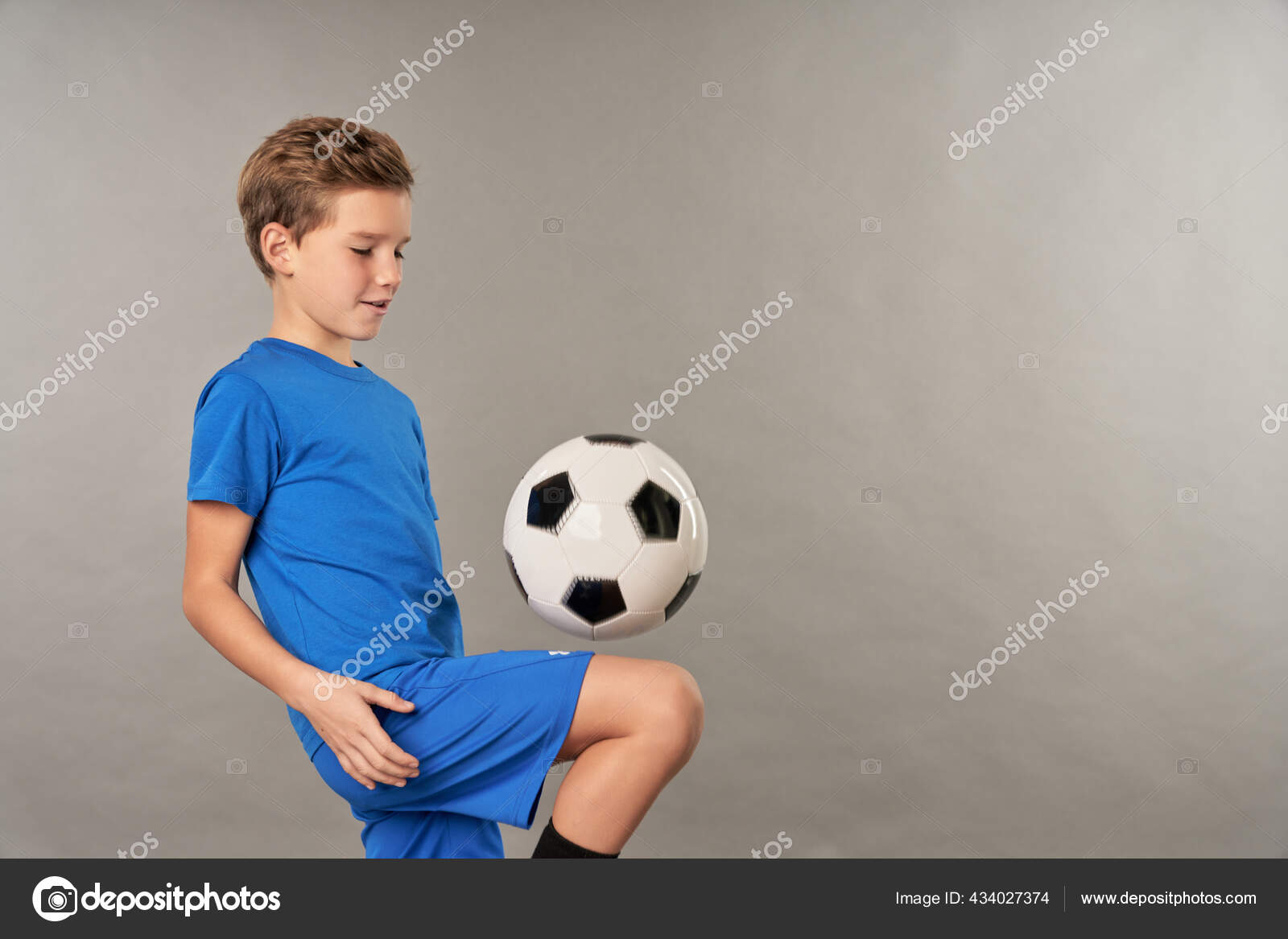 Jogador de futebol forte com bola de futebol e sorrindo em fundo branco  isolado