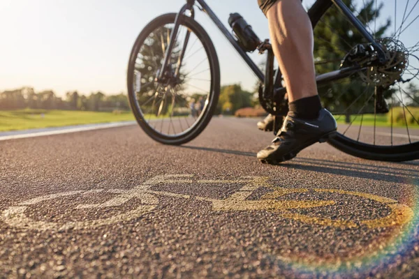 Close up of a bicycle sign drawn on asphalt. Professional male cyclist standing with his road bike on a cycle path
