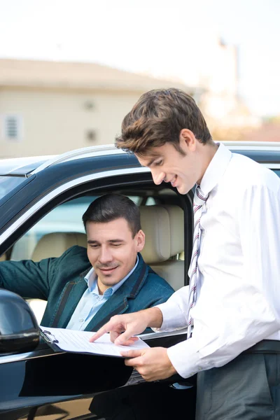 Car dealer and young man signing a contract