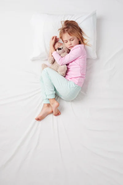 Top view of little girl sleeping with teddy bear
