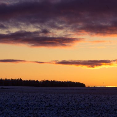 Güzel, parlak, renkli bir kış gündoğumu manzarası. Parlak gökyüzü ve ilk kar. Güneş doğarken Kuzey Avrupa 'nın kış manzarası.