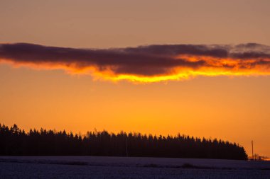 Güzel, parlak, renkli bir kış gündoğumu manzarası. Parlak gökyüzü ve ilk kar. Güneş doğarken Kuzey Avrupa 'nın kış manzarası.