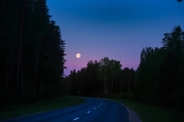 A beautiful full moon shining low in the sky during the summer dawn. Summertime scenery of Northern Europe.