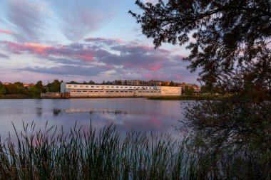 Endüstriyel bölgenin güzel akşam manzarası batan güneşi yansıtan binalar. Riga, Letonya.