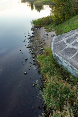 Ağaçlı bir gölün kıyısında güneşli bir sonbahar sabahı. Letonya 'nın parlak, renkli manzarası.