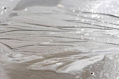 Baltık Denizi sahilinde akan su tarafından yapılan güzel süs kumu desenleri. Letonya 'da güneşli bir yaz günü.