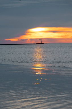 Güzel bir gün batımı manzarası. Uzakta küçük bir deniz feneri var. Renkli akşam gökyüzüne karşı. Riga, Letonya 'da yaz akşamı.