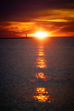 Güzel bir gün batımı manzarası. Uzakta küçük bir deniz feneri var. Renkli akşam gökyüzüne karşı. Riga, Letonya 'da yaz akşamı.