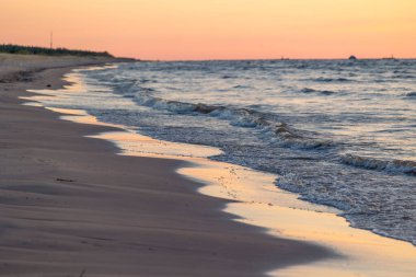 Gün batımındaki deniz dalgalarının soyut ve minimalist bir resmi. Sığ alan derinliği, Bokeh, yakın hasat. Letonya, Avrupa 'da yaz akşamı. Baltık Denizi kıyısı.