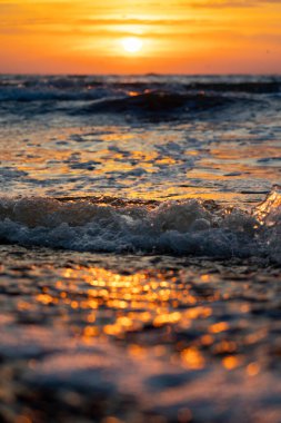 Gün batımındaki deniz dalgalarının soyut ve minimalist bir resmi. Sığ alan derinliği, Bokeh, yakın hasat. Letonya, Avrupa 'da yaz akşamı. Baltık Denizi kıyısı.