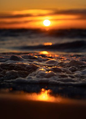 Gün batımındaki deniz dalgalarının soyut ve minimalist bir resmi. Sığ alan derinliği, Bokeh, yakın hasat. Letonya, Avrupa 'da yaz akşamı. Baltık Denizi kıyısı.
