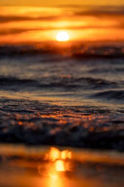 Gün batımındaki deniz dalgalarının soyut ve minimalist bir resmi. Sığ alan derinliği, Bokeh, yakın hasat. Letonya, Avrupa 'da yaz akşamı. Baltık Denizi kıyısı.