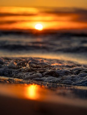 Gün batımındaki deniz dalgalarının soyut ve minimalist bir resmi. Sığ alan derinliği, Bokeh, yakın hasat. Letonya, Avrupa 'da yaz akşamı. Baltık Denizi kıyısı.