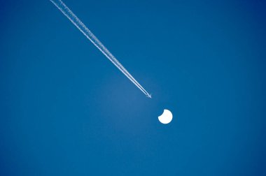 Güneşin kısmi tutulması ve uçağıyla güzel, berrak bir gökyüzü. Letonya, Avrupa 'da bahar manzarası.