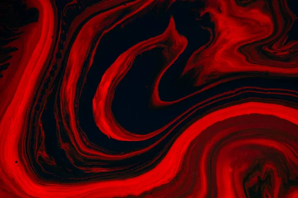 Fluid art texture. Background with abstract iridescent paint effect. Liquid acrylic picture that flows and splashes. Mixed paints for posters or wallpapers. Orange, red and black overflowing colors.